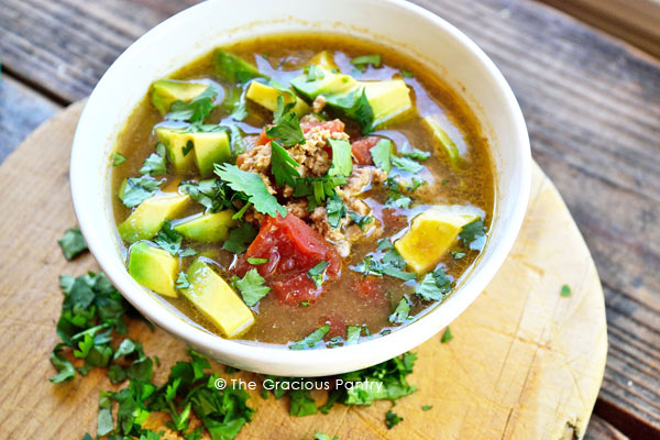 Clean Eating Slow Cooker Taco Soup Recipe overhead view showing a white bowl filled with the soup sitting on a cutting board.