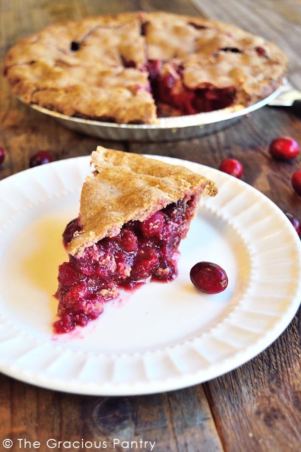 slice of cranberry pie on a white plate with remaining pie behind it