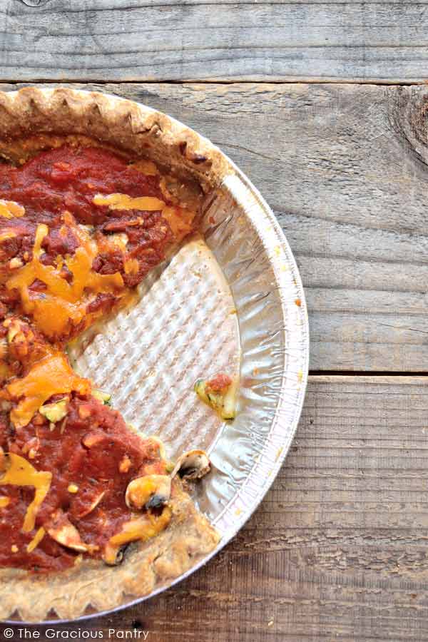 Clean Eating Pizza Pie shown in the pie pan it was baked in. One slice has been removed from the pan.