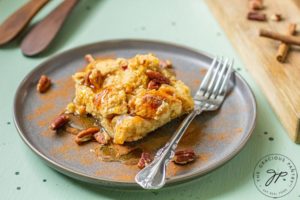 A slice of this Pumpkin Spice French Toast Casserole Recipe sits on a plate with a fork, ready to enjoy for breakfast.