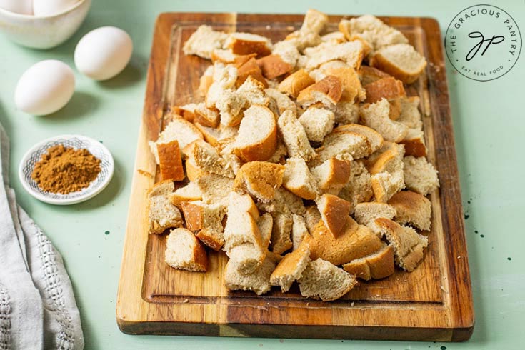 The whole grain bread lays on a cutting board, cut into little, bite-sized pieces.