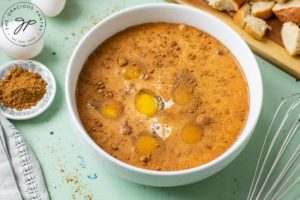 A bowl sits filled with eggs and pumpkin spice, ready to whisk and pour.