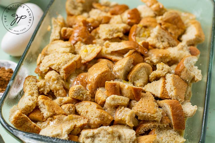 Bread sits in casserole dish with egg mixture poured over it, ready to bake.