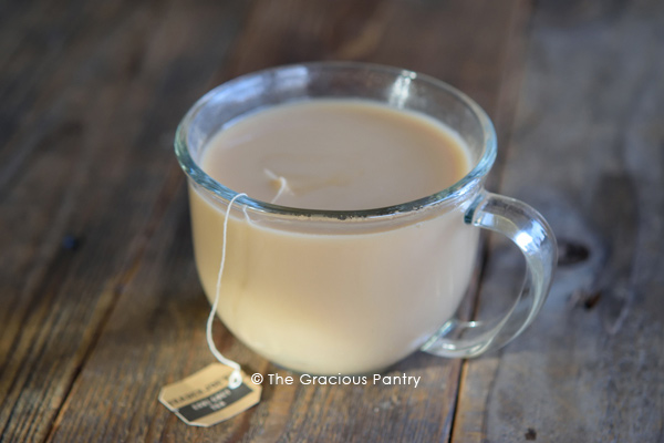 A London Fog in a glass mug on a wooden table.