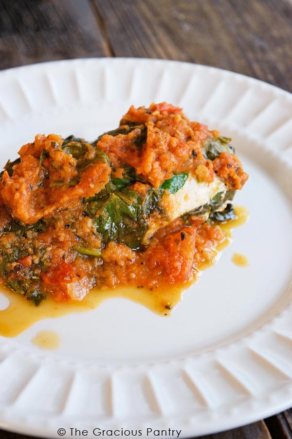 A single white plate holding a servings of this Clean Eating Instant Pot Spinach Chicken.