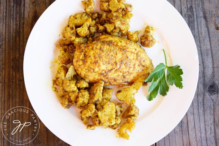 Clean Eating Sheet Pan Chicken And Cauliflower shown from overhead looking down onto the white plate of food.