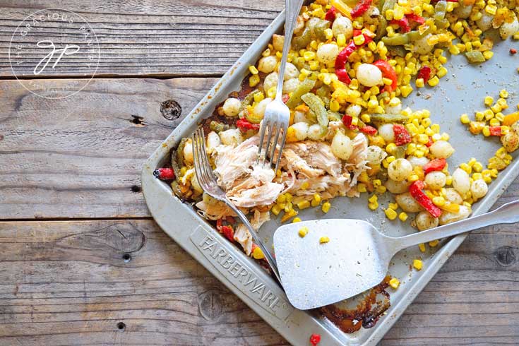 This Clean Eating Sheet Pan Mexican Chicken Dinner Recipe can also be shredded for taco filling. This image shows the chicken already shredded and still laying next to the vegetable on the sheet pan.