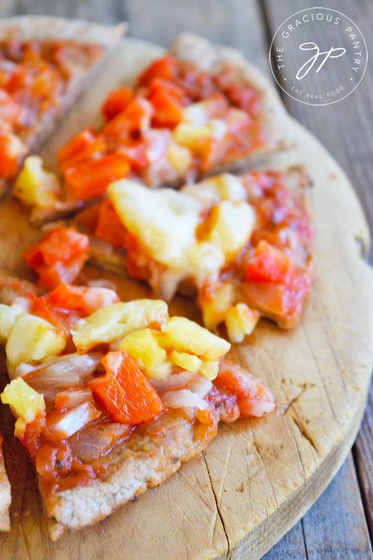 Close up of a cute Hawaiian Pita Pizza on a cutting board.