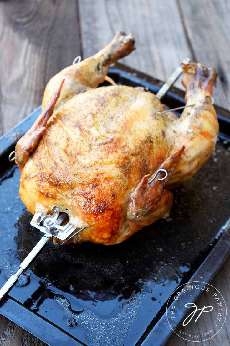 A whole chicken on a rotisserie stick.