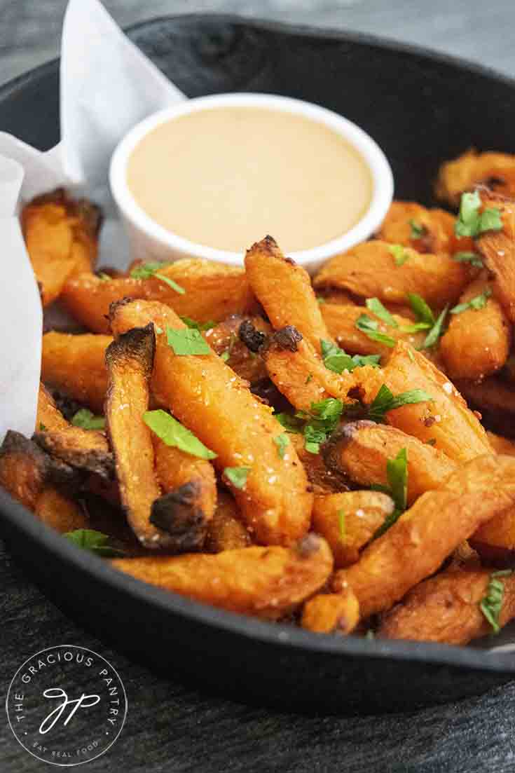 A side view of a black skillet filled with these Air Fryer Sweet Potato Fries.