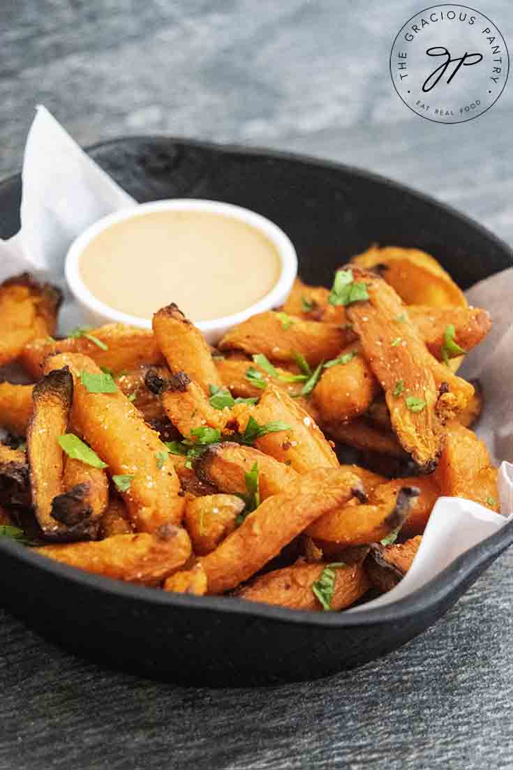 A cast iron skillet filled with fries and dipping sauce.