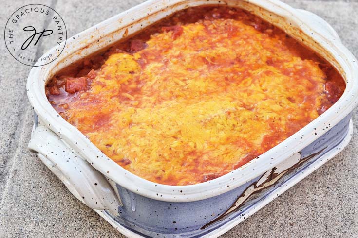 A filled casserole dish topped with red sauce and melted cheddar cheese.