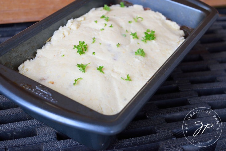 Clean Eating Turkey Vegetable Meatloaf Casserole recipe still in the loaf pan. You can see the layer of mashed cauliflower on top sprinkled with specks of fresh parsley.