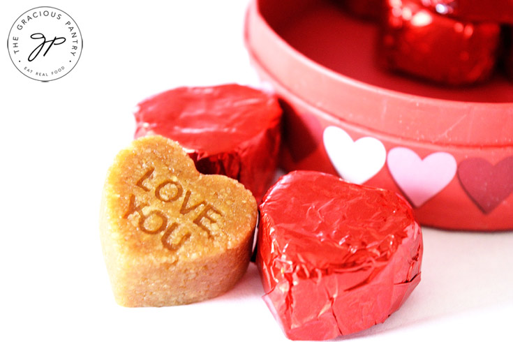 A closeup of three candies from this marzipan candy recipe. Two are wrapped in red foil, the third is unwrapped.