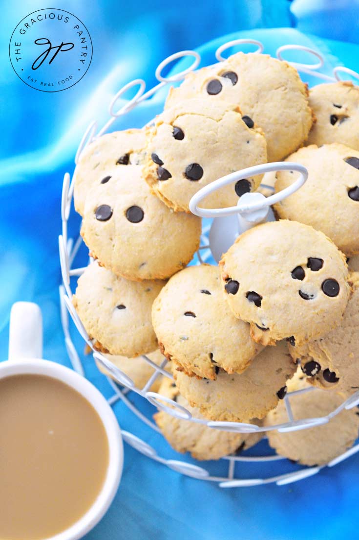 A two tiered platter holds an entire batch of Tea Biscuits With Lavender and Chocolate Chips. A cup of coffee sits next to the platter.