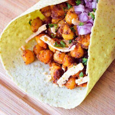 A folded tortilla stuffed with seasoned chickpeas sits on a cutting board.