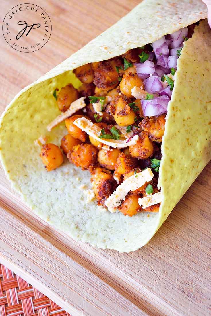 A folded tortilla stuffed with seasoned chickpeas sits on a cutting board.