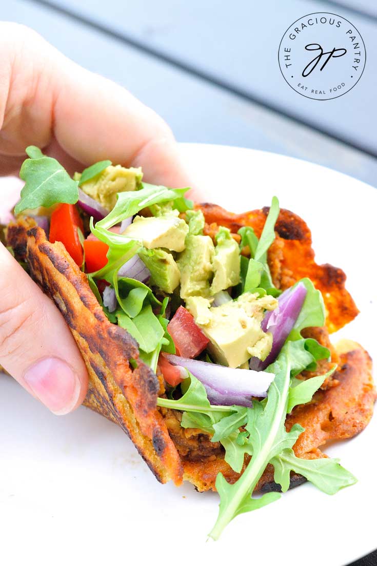A folded tortilla filled with this Clean Eating Chickpea Tacos recipe for the filling and topped with arugula, tomatoes and avocado.