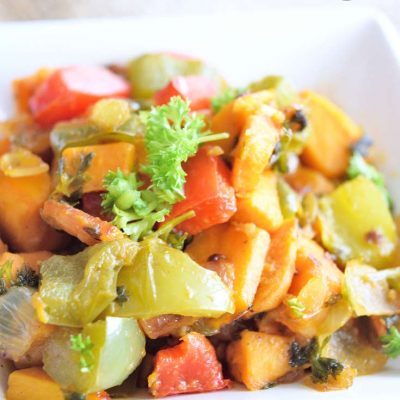 Sweet Potatoes O Brien in a square, white dish with chunks of sweet potatoes, green, and red bell peppers