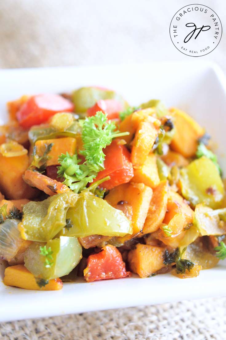 Sweet Potatoes O Brien in a square, white dish with chunks of sweet potatoes, green, and red bell peppers