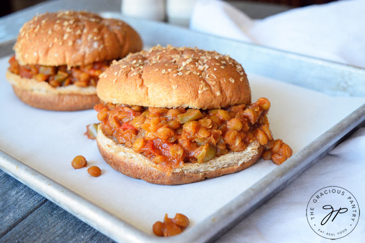 A second view of these Clean Eating Lentil Sloppy Joes better shows both sandwiches, one behind the other. You can see the lentils with bits of pepper throughout, in between the whole grain burger buns.