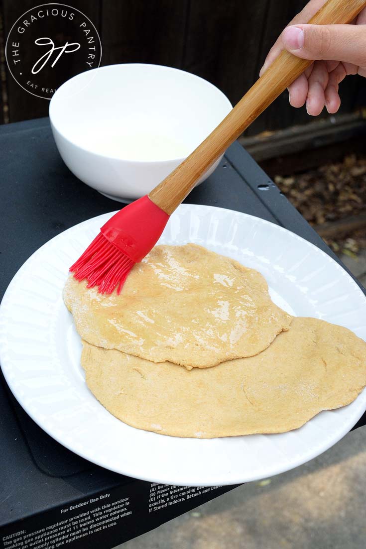 making a flatbread recipe by basting dough with melted butter