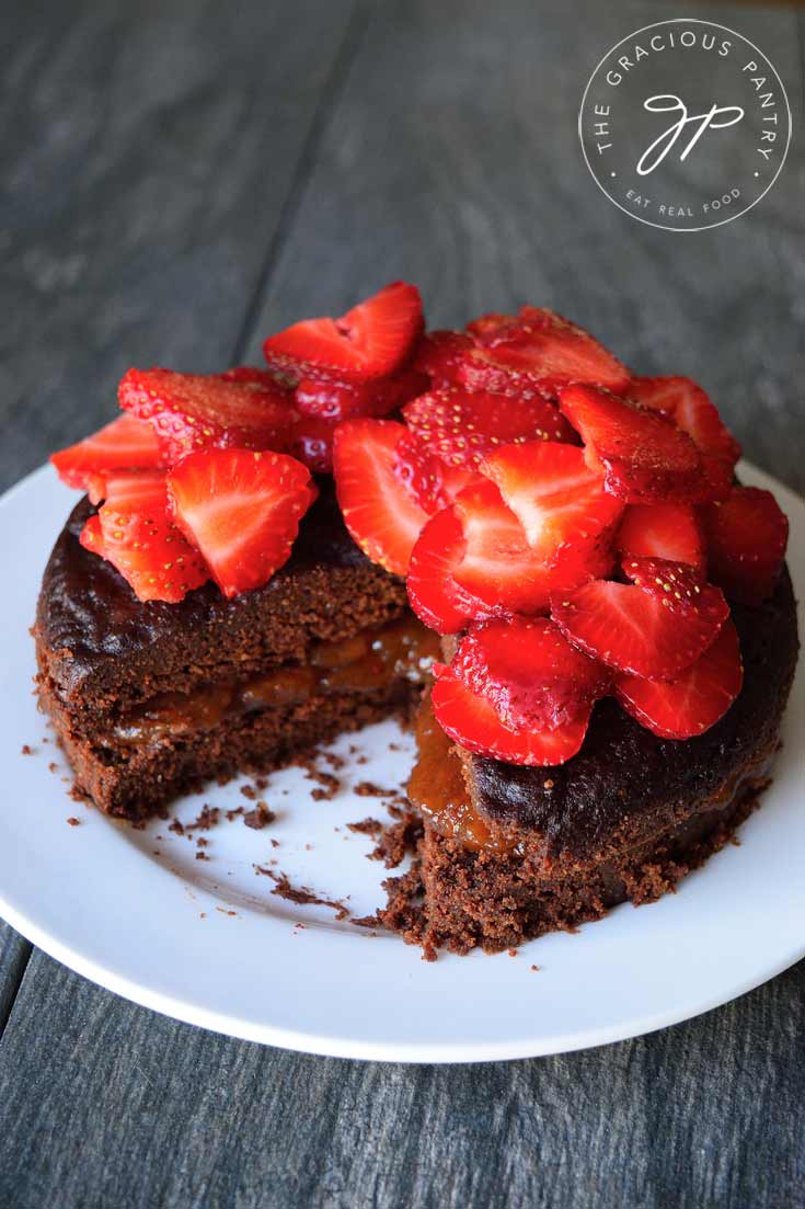 A front view of this Instant Pot chocolate cake on a white platter, topped with strawberries.