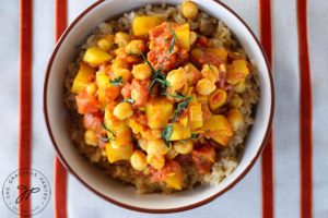 Bombay Potatoes in a bowl sitting on a striped cloth.