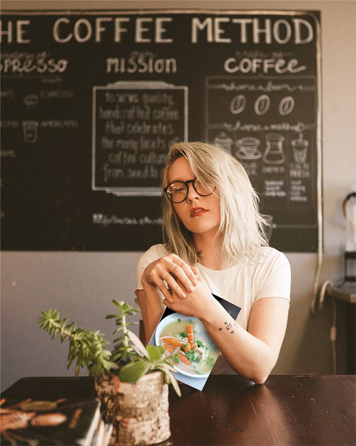 Blond woman in a coffee shop holding the clean eating freezer meals cookbook in her hands.