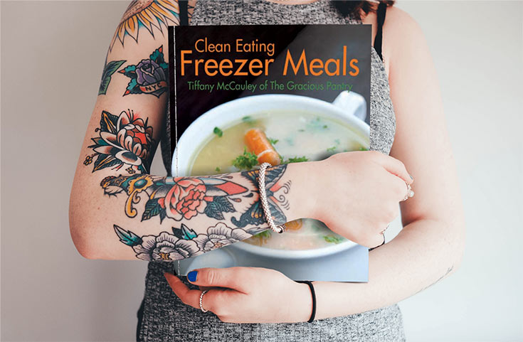 A woman holding the clean eating freezer meals, cradled in her arms at her chest.