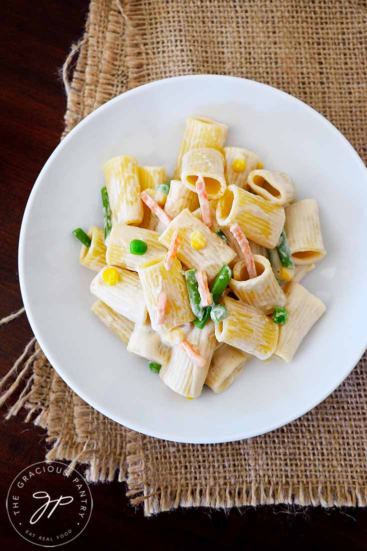 An overhead view of this Clean Eating Creamy Vegetable Pasta in a white bowl. You can see bits of corn, green beans and carrots as well as the creamy cashew sauce.