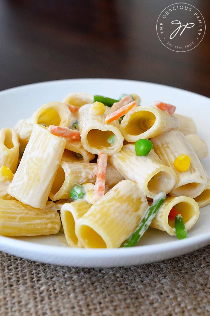 A side view of this dish shows the pasta in a white bowl. You can see into the round rigatoni noodles from the side. There are bits of the mixed veggies in with the sauce that is coating the noodles.