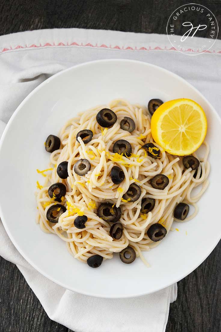 An overhead view of this Clean Eating Olive Pasta shows the lemon, lots of black olives throughout the pasta, and a tiny bit of lemon zest sprinkled over the top for garnish.