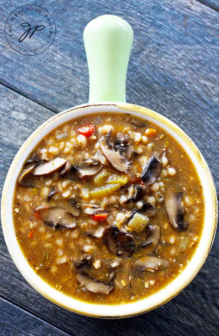 An overhead view of this mushroom barley soup shows all of the beautiful pieces of veggies. Orange carrots, light brown barley and dark brown mushrooms, ready to eat.