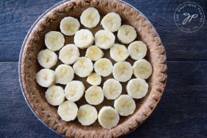 Step 2 of building this clean eating banana cream pie shows the sliced banana layer over the custard layer.