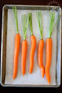 A tray of carrots sits ready to be dressed for roasting in this clean eating maple glazed carrots recipe.