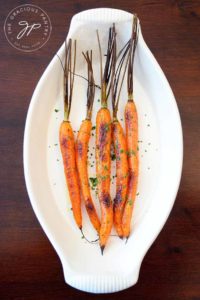An overhead look at these clean eating maple glazed carrots. They sit in an off white, oval serving dish.