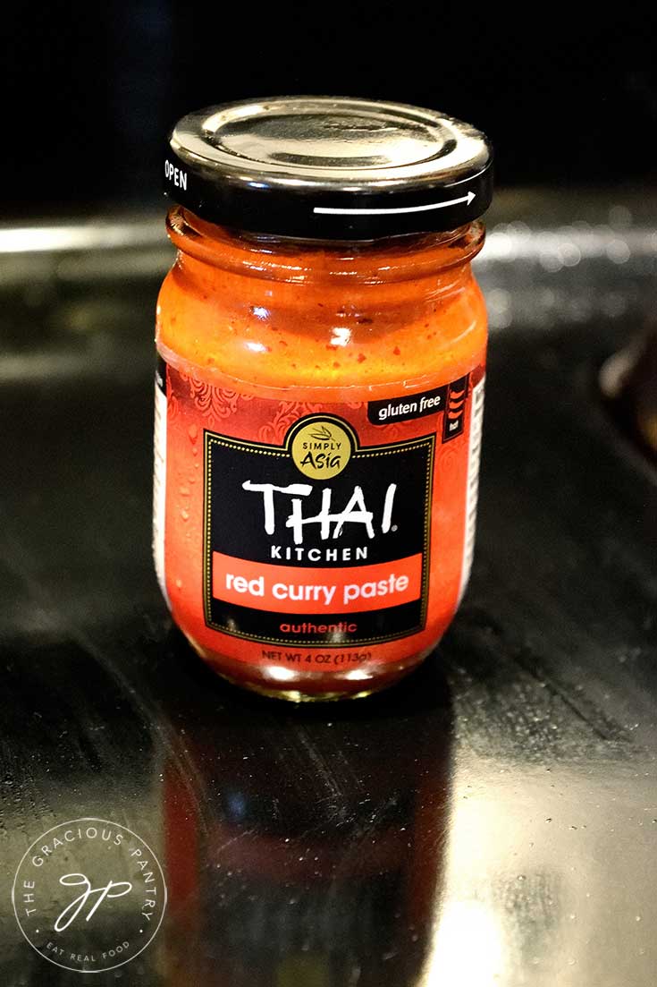 A bottle of Thai Kitchen's Red Curry Paste sits on a black background showing one of the ingredients in this clean eating Thai ramen soup recipe.
