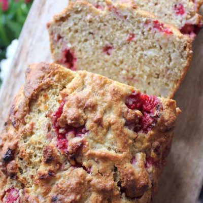 A few slices are cut and laying next to this loaf of Clean Eating Raspberry Vanilla Banana Bread.