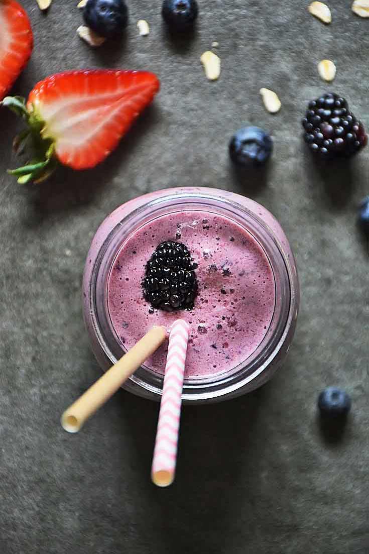 An overhead view of this Mixed Berry Smoothie, looking down into the jar. You can see the pretty lavender-pink color of the smoothie, the blackberry sitting on top and the two straws begging you to take a sip.