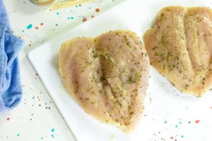 The first step in this air fryer chicken breasts recipe is to butterfly the chicken breasts and rub them with oil and spices.