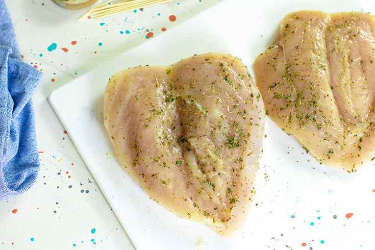 The first step in this air fryer chicken breast recipe is to butterfly the chicken breasts and rub them with oil and spices.