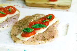 The next step in this Air Fryer Chicken Breasts Recipe is to layer the cheese, tomatoes and fresh basil onto the butterlied chicken breasts.