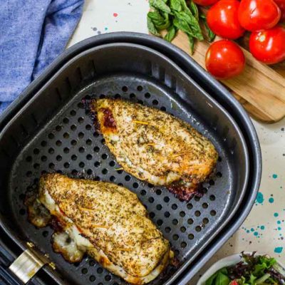 This chicken from this Air Fryer Chicken Breast Recipe still sits in the air fryer basket after just finishing the cooking cycle. Two cooked breasts sit in the basket, ready to serve.