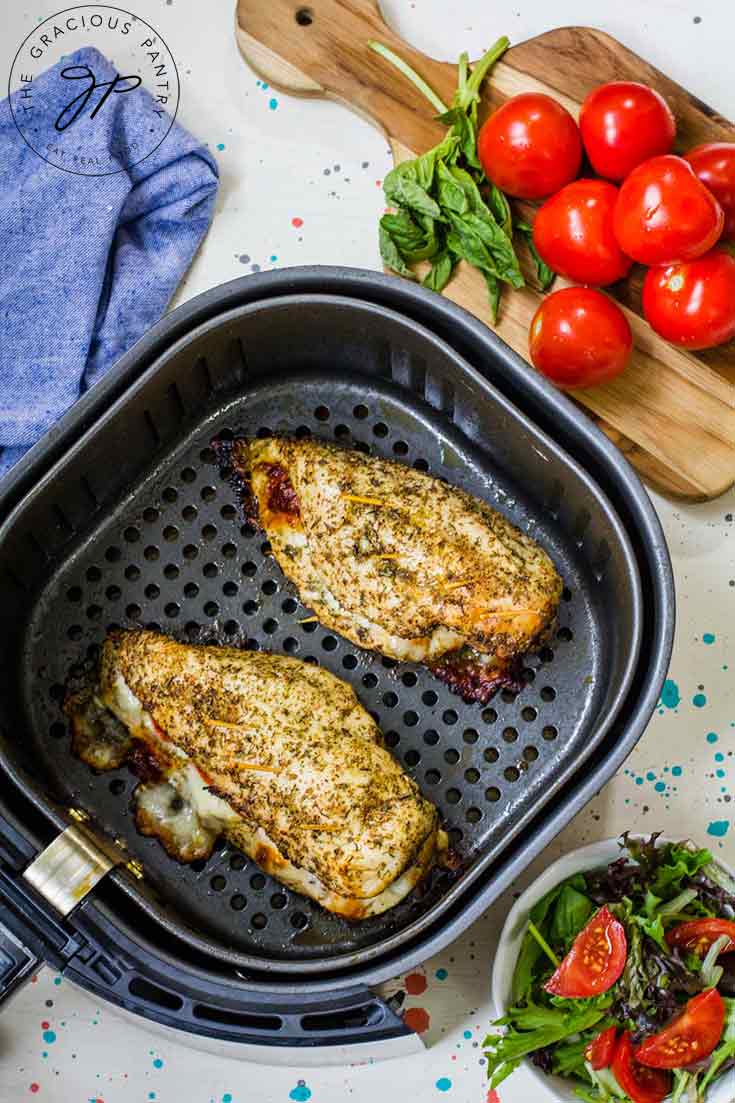 This chicken from this Air Fryer Chicken Breast Recipe still sits in the air fryer basket after just finishing the cooking cycle. Two cooked breasts sit in the basket, ready to serve.