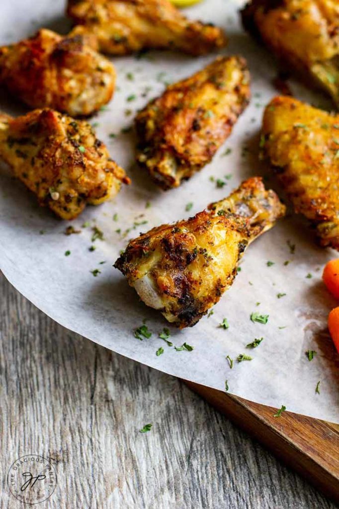 A cutting board with air fryer chicken wings sits with a small pile of baby carrots next to it.