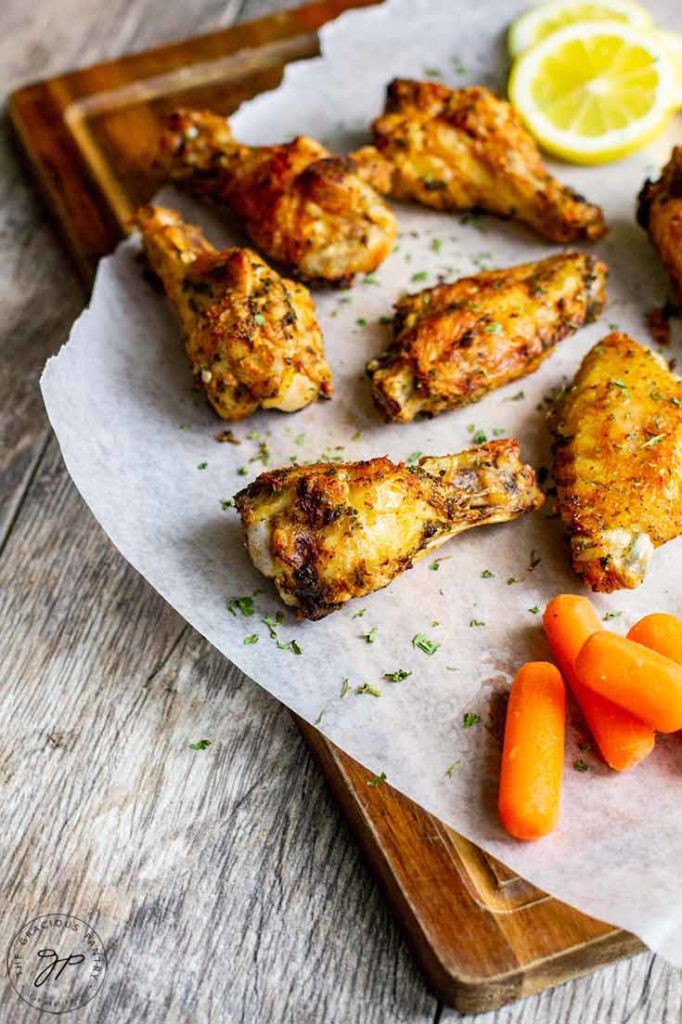 This Air Fryer Chicken Wings Recipe is done cooking and ready to eat with some baby carrots and lemon slices on the side.