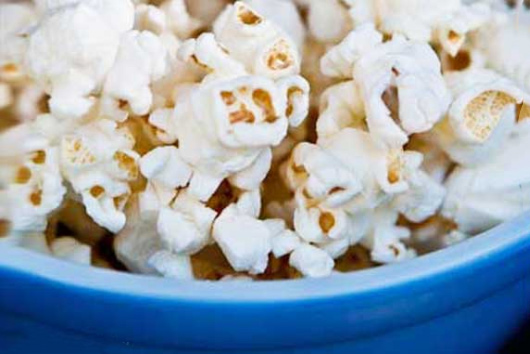 A blue bowl sits filled with fresh popcorn in this guide to after school snacks that won't ruin dinner.