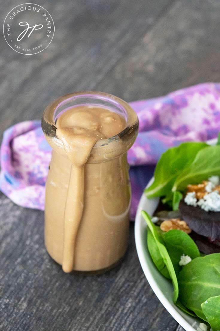 A singular jar sits filled with this blue cheese vinaigrette. A small spill of dressing drips down the side of the jar.