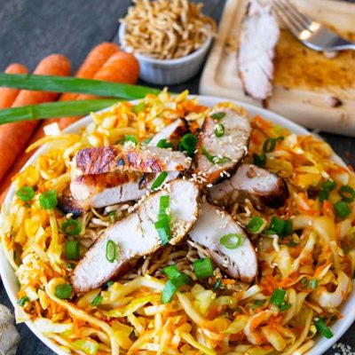 A Chinese Chicken Salad sits in a white bowl with recipe ingredients surrounding it.